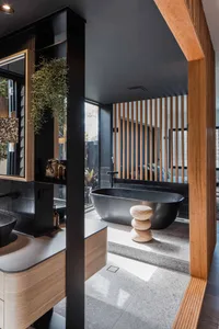 Modern bathroom featuring granite bathtub, wooden accents, and concrete floor tiles.