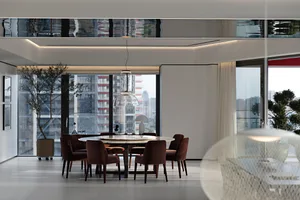 A modern dining room featuring a round table and chairs surrounded by a glass window.