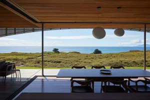 Modern residential interior featuring wood, glass, and metal materials with a sea view.