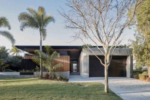 Modern house featuring concrete and wood exteriors surrounded by greenery.