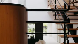 Modern interior design featuring a metal and wood staircase with black handrails.