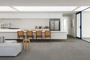 A modern kitchen with white cabinets and appliances, featuring a long island with seating.