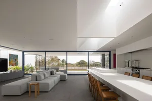 A modern living room with large glass windows allowing natural light in, an open-plan layout, and a comfortable seating area.