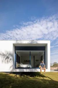 A modern minimalist house with a white exterior, glass windows, and concrete elements.