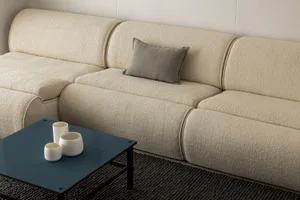 A modern sectional sofa with a textured fabric upholstery in a minimalist living room setting.