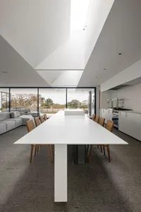 Modern white concrete dining room with large windows and natural light.