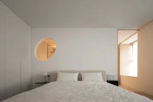 A minimalist bedroom with a fabric-covered bed and light wood accents