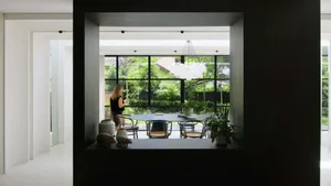 A modern dining room with a black metallic chandelier hanging above a table surrounded by chairs, featuring a minimalist desi