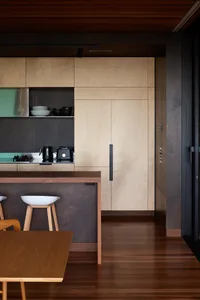 Modern minimalist kitchen featuring wood cabinets and flooring.