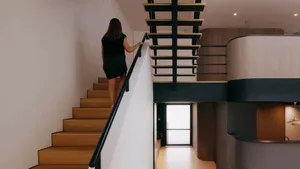 A woman descends a modern industrial staircase made of metal and wood.