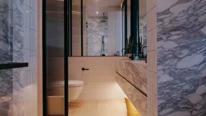A modern bathroom with marble walls and black accents.