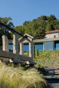 Modern, outdoor sculpture made of stone and metal with green grass in the foreground