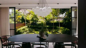 Modern residential dining room featuring a black oval table with chairs, a white balloon cloud chandelier, and a green outdoo