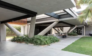 A modern residential exterior featuring concrete, glass, and metal elements.