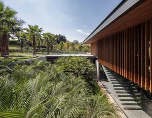 Modern residential exterior featuring a wooden exterior with large glass windows and a concrete foundation.