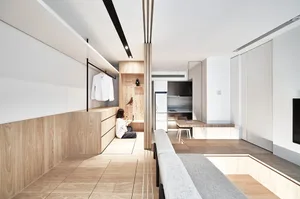 A minimalist apartment with wooden and white finishes and a person sitting on the floor.