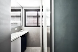A minimalist bathroom with concrete walls and floor, featuring window blinds and modern fixtures.