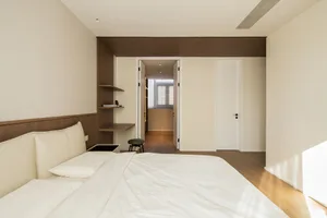 A minimalist bedroom with neutral-toned textiles and a modern design.