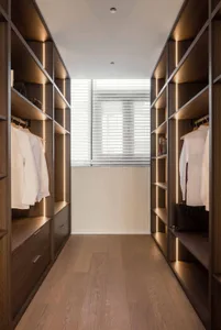 Modern minimalist closet with wooden cabinets, LED lighting, and a large mirror.