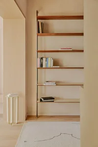 A minimalist shelf with books and objects in a beige room.