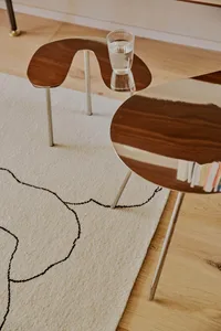 A stylish coffee table set with metal and walnut wood finishes and a glass top, featuring a contemporary design and sleek, mi