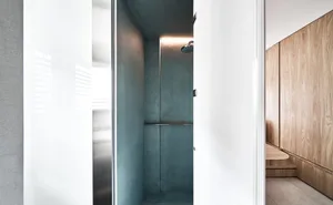 A minimalist bathroom with gray concrete walls and a chrome shower head.