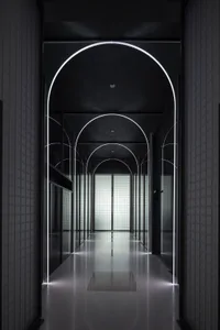 A modern interior corridor with glass walls and recessed lighting.