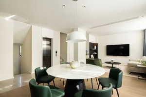 Contemporary living room with marble table and green chairs.