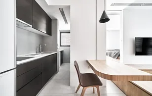 Modern kitchen with black cabinets, white countertops, and wooden table.