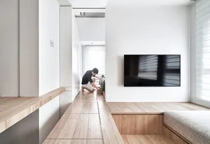 A minimalist living room with wood flooring and furniture.
