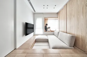 A well-designed minimalist living room with light-colored wooden flooring, a wooden and textile sofa, and a window seat area.