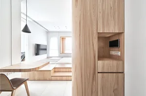 A minimalist white interior with wood elements and a wall-mounted TV.