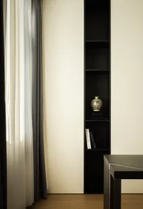 A minimalist home office setting with black bookshelf, wooden floor, and modern design.