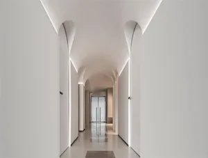A minimalist white corridor with curved white walls and a glossy floor, featuring recessed lighting and a view to the end of 