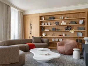 A modern living room with a marble coffee table, wooden shelves, and upholstered furniture.