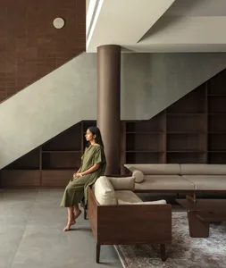 A modern living room with a wooden sofa, a coffee table, and a bookshelf in the background.