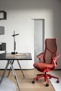 Modern office setup featuring a red ergonomic chair with metallic frame and a rectangular metallic table.