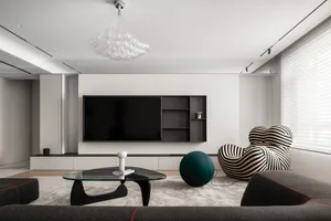 Modern living room with black, white, and green accents, featuring an abstract black frame table, black and white striped arm