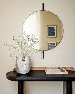 A modern interior design featuring a ceramic vase with dried flowers and a round mirror on the wall, books placed on a dark t
