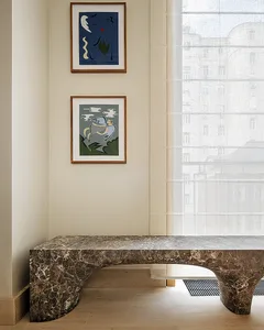 A modern interior space featuring a curved marble bench and two framed artworks on the wall.