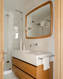 A modern bathroom featuring a concrete countertop and wooden vanity with a large mirror and glass shower enclosure.