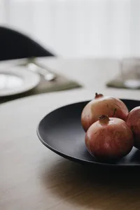A modern interior design ceramic fruit bowl featuring a bowl filled with organic apples placed on a wooden countertop.