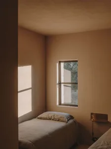 A minimalist bedroom with neutral-colored walls and a single window.
