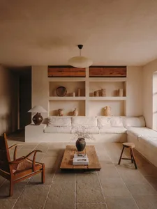 A minimalist living room with a concrete floor, wood furniture, and built-in shelves.