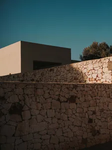 A modern building featuring a stone wall during sunset.