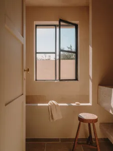 Minimalist bathroom featuring concrete walls and floor with an open window.