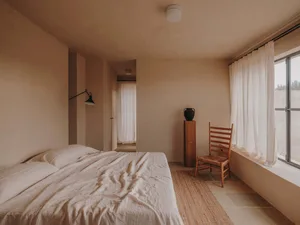 A minimalist bedroom featuring soft materials such as fabric and wood.