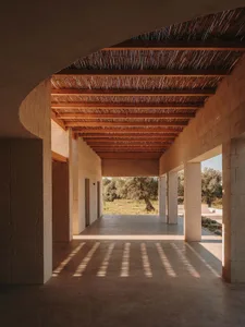A minimalist interior with concrete floor and wooden beams in a building.