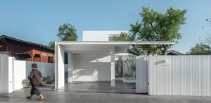 A minimalist house with a white exterior, featuring concrete and metal materials.