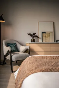 A modern bedroom featuring wooden furniture, upholstered fabric seating, and woven decorative accents.
